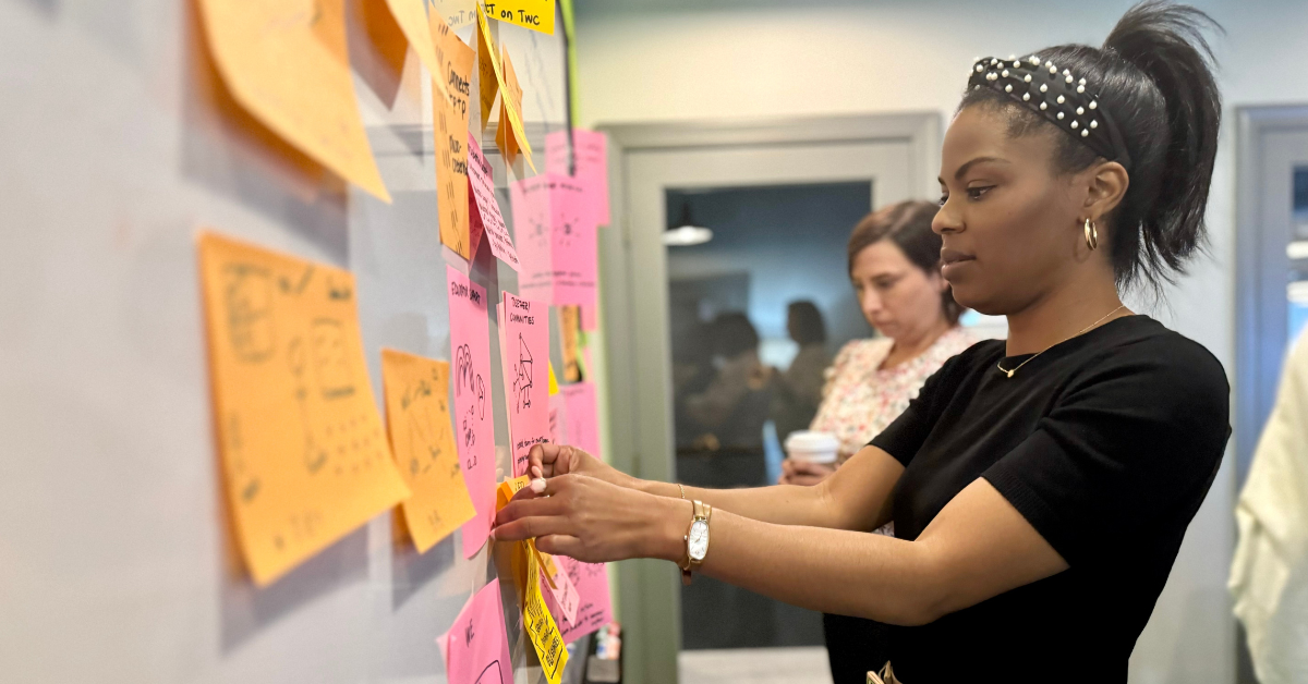 Image of a woman adjusting sticky notes on a white board